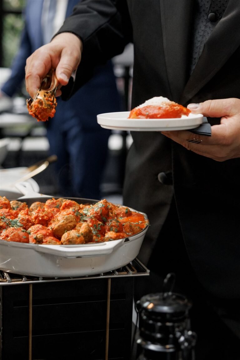 Guest takes a bite-sized appetizer from a chafing dish at a food station