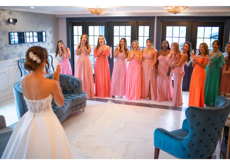 Bride greets bridesmaids in coral and pink gowns in the Park Loft bridal suite