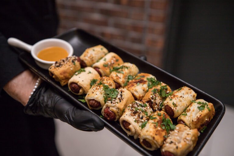 Server holds a tray of spring rolls with a dipping sauce during cocktail hour