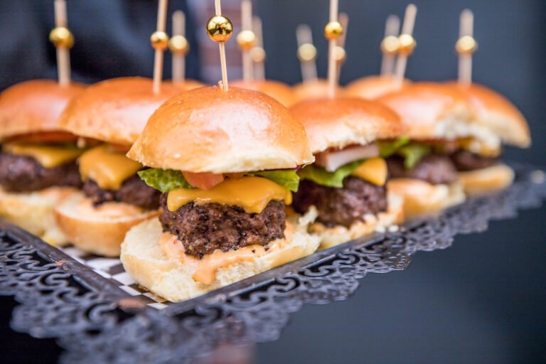 Tray of cheeseburger sliders with gold picks served during cocktail hour