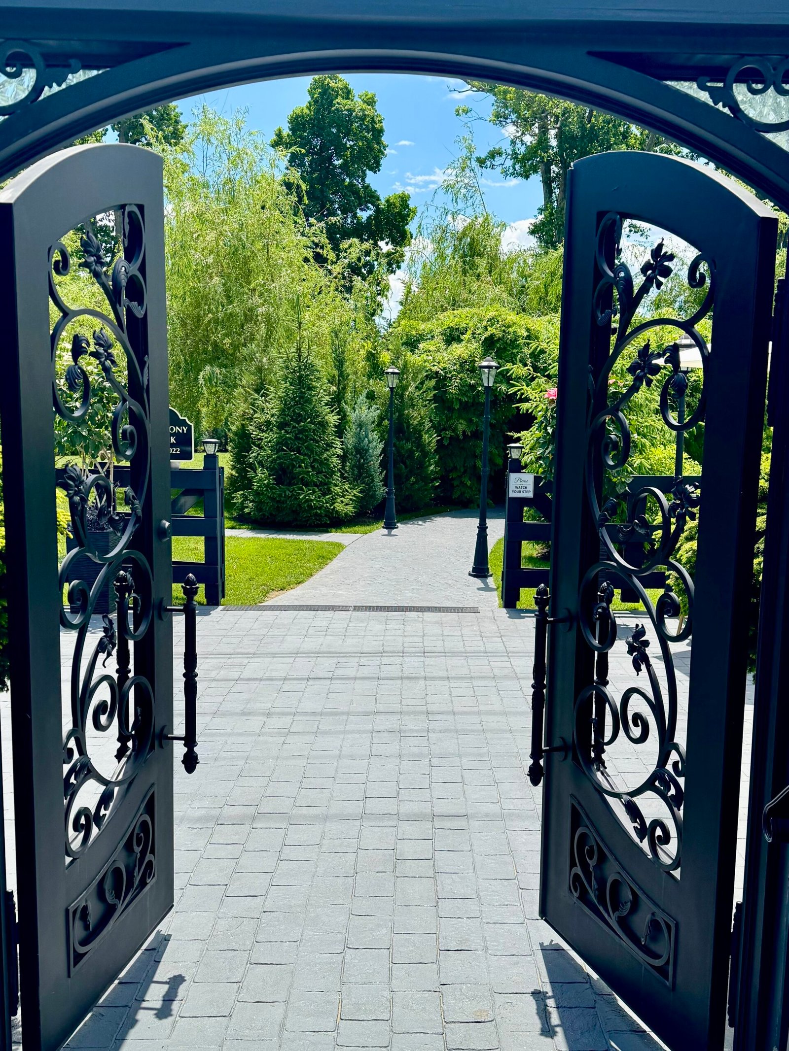 Ornate black wrought-iron gates open onto a paved garden walkway at Park Loft