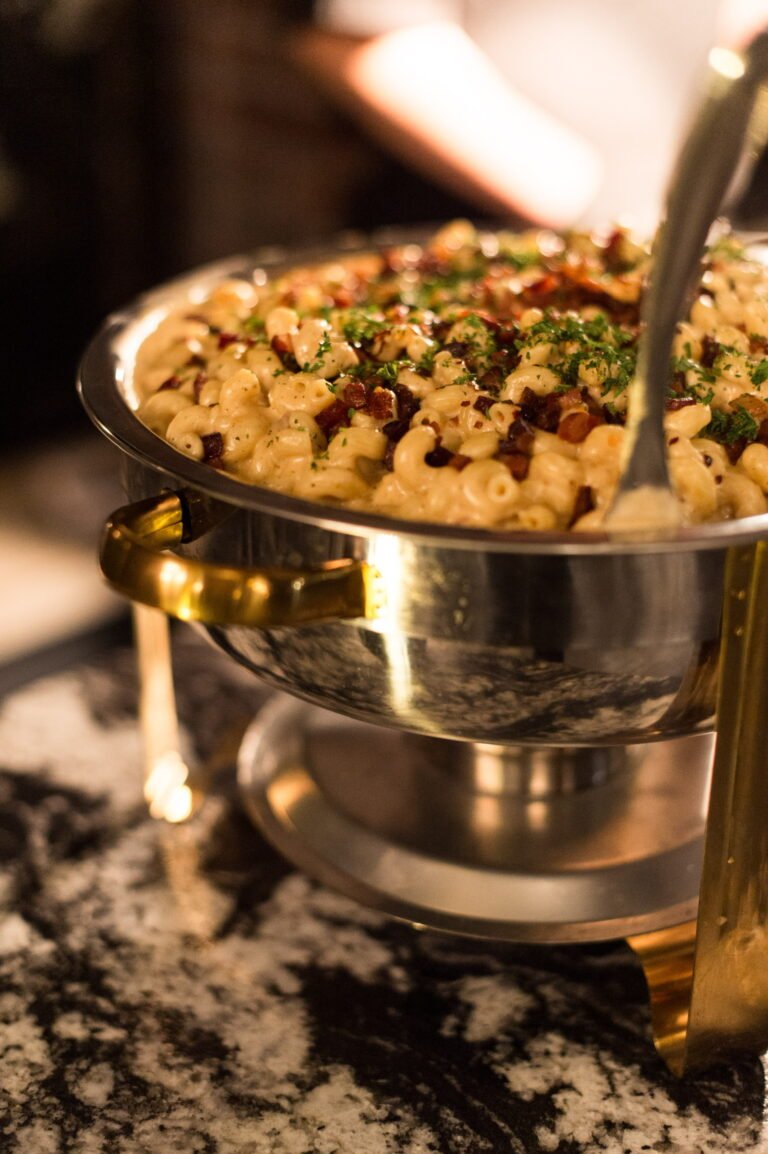 Chafing dish of baked pasta with a serving spoon on the buffet