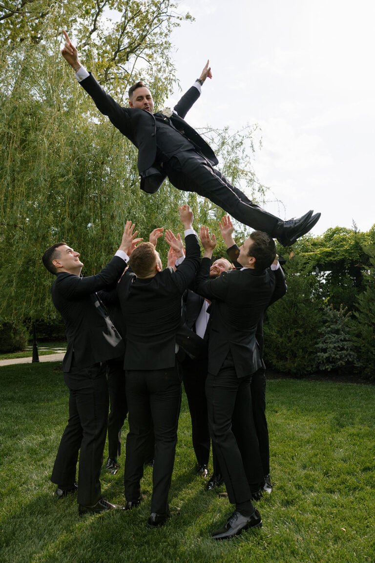 Groomsmen toss the groom into the air on the Park Loft lawn