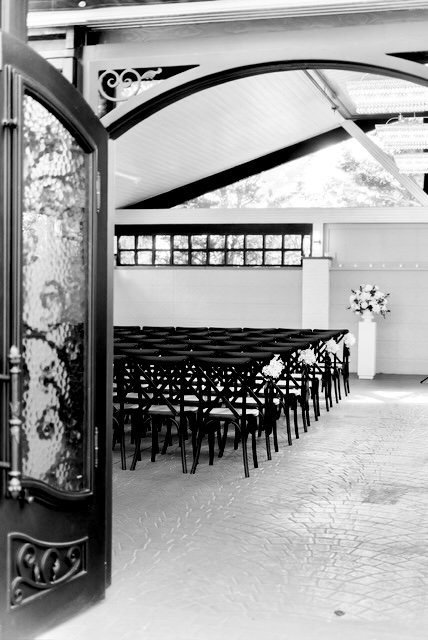 Black-and-white view through wrought-iron doors into the Park Loft atrium set with ceremony chairs