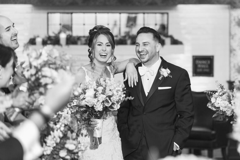 Black-and-white photo of a bride and groom laughing together at their reception