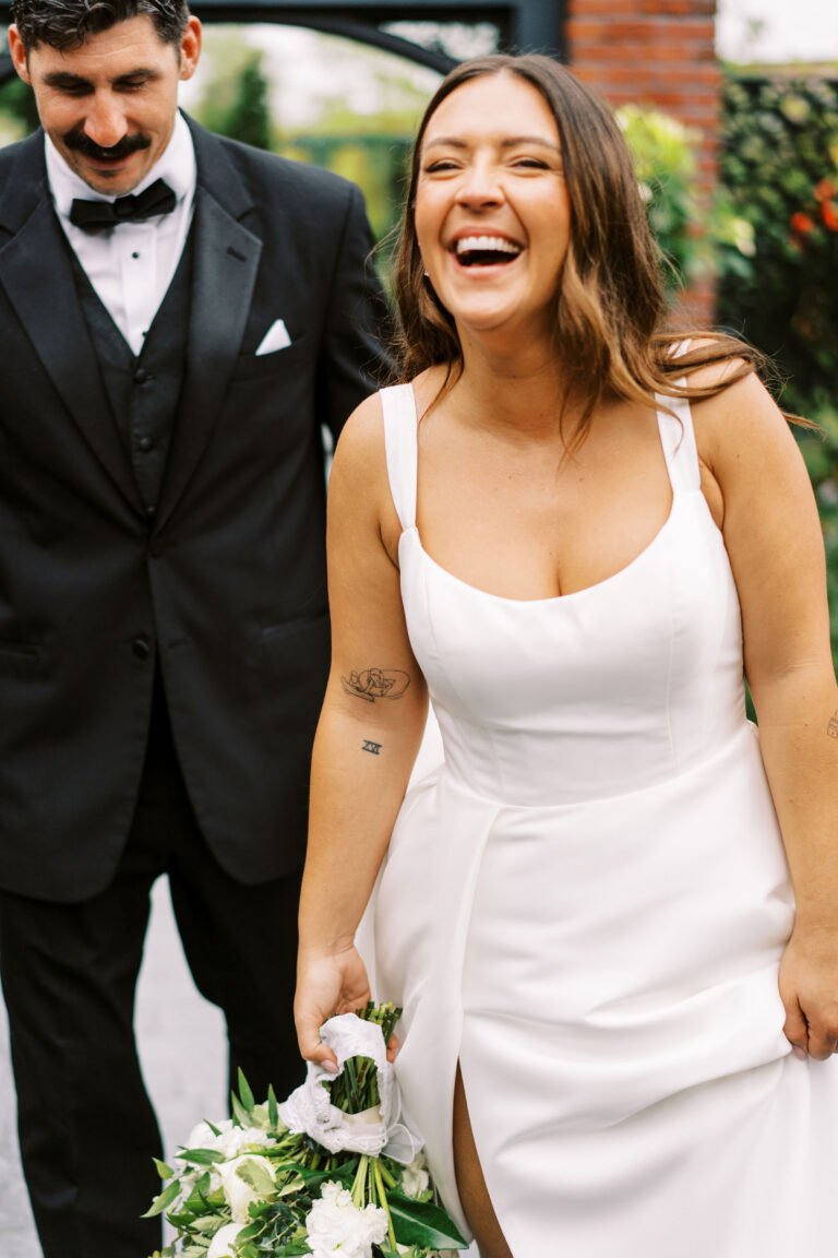 Bride laughs with the groom while holding her bouquet outdoors