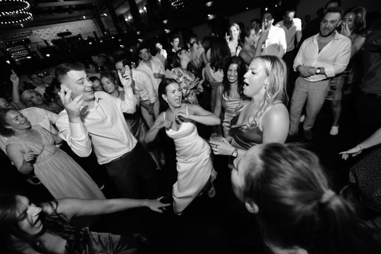 Black-and-white photo of the bride dancing with friends on a packed dance floor