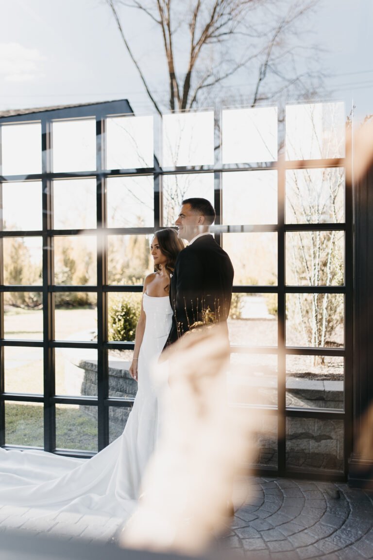 Bride and groom embrace in front of the black-framed windows of the Park Loft atrium