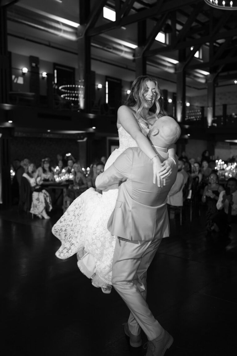 Black-and-white photo of the groom carrying the bride across the Park Loft dance hall