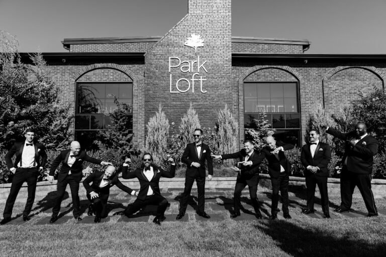 Black-and-white photo of the groom and groomsmen striking a playful pose in front of the Park Loft building