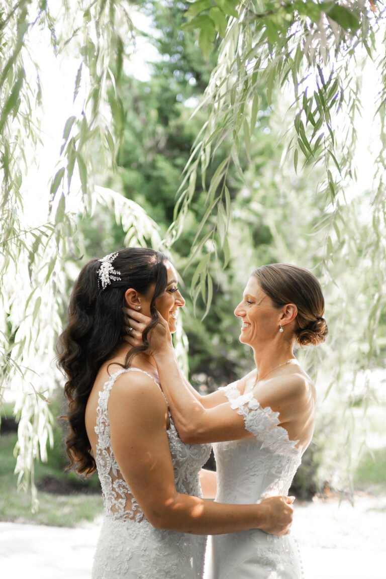 Bride shares a tender moment with a loved one beneath a willow tree