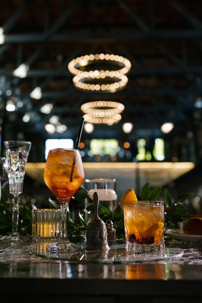Craft cocktails on the bar with glowing ring chandeliers overhead