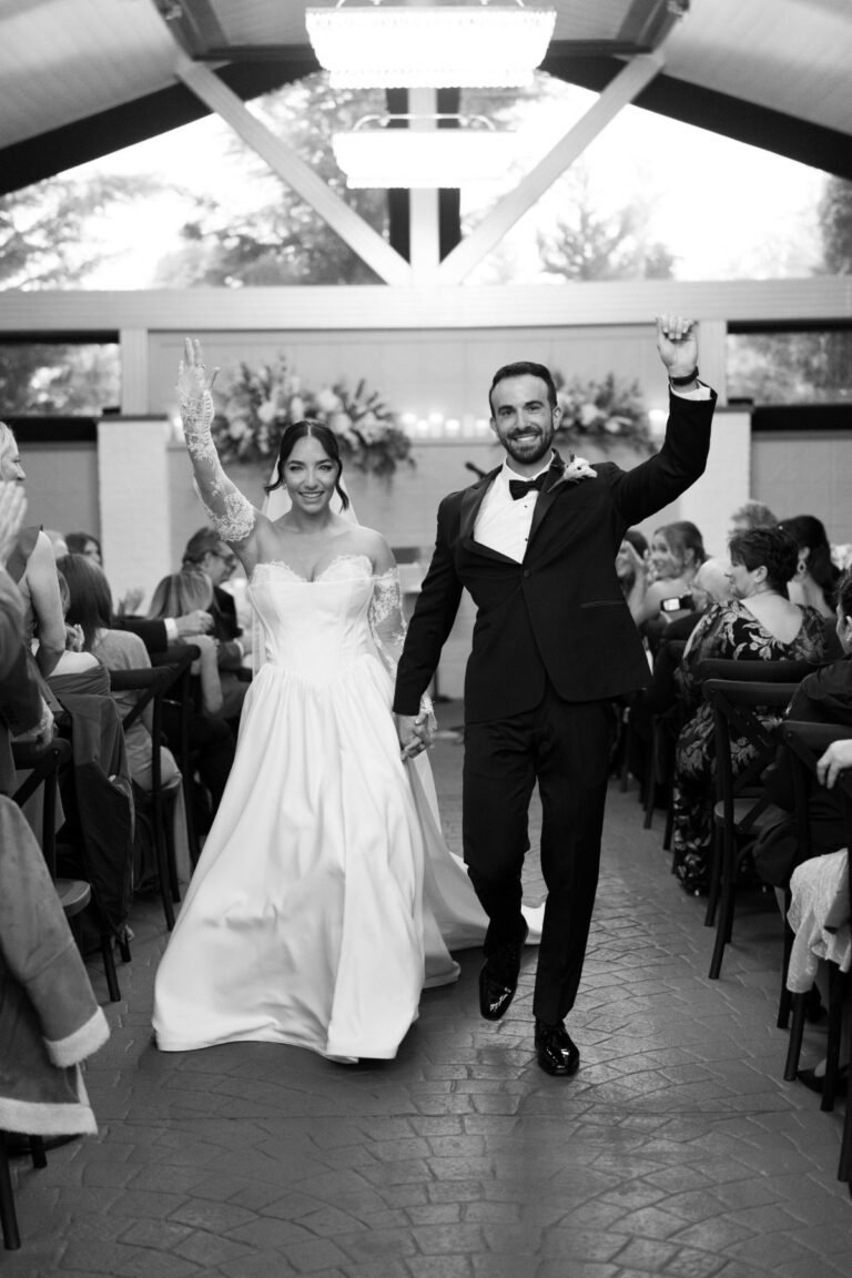 Black-and-white photo of newlyweds celebrating as they walk back up the aisle