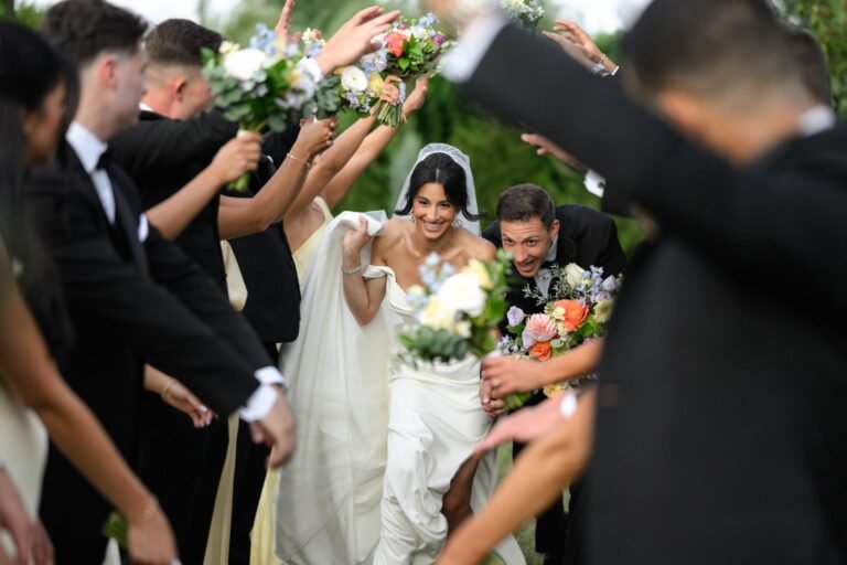 Bride and groom duck through an arch of bouquets held by their wedding party