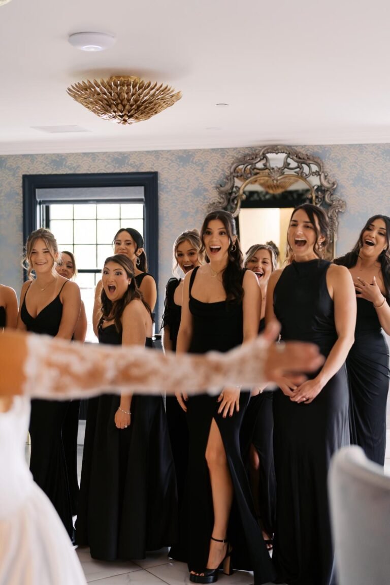 Bridesmaids in black gowns watch as the bride approaches in the bridal suite