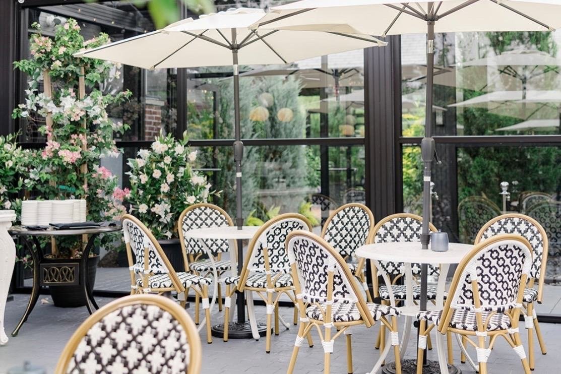 Outdoor patio at Park Loft with market umbrellas, rattan bistro chairs and flowering greenery