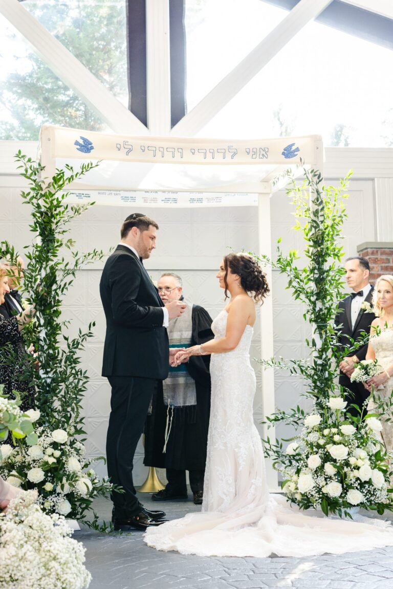 Couple exchanges vows beneath a greenery-draped ceremony arch